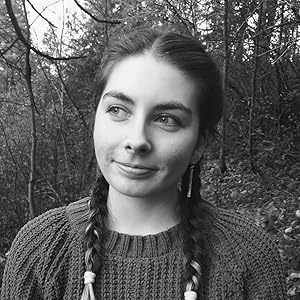 Black and white portrait of Daphne Paige, a young woman with braided hair, wearing a knit sweater, standing in a wooded area and gazing thoughtfully into the distance.